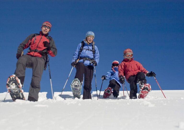 snowshoeing vs cross country skiing A family of four enjoys a snowshoeing excursion on a bright